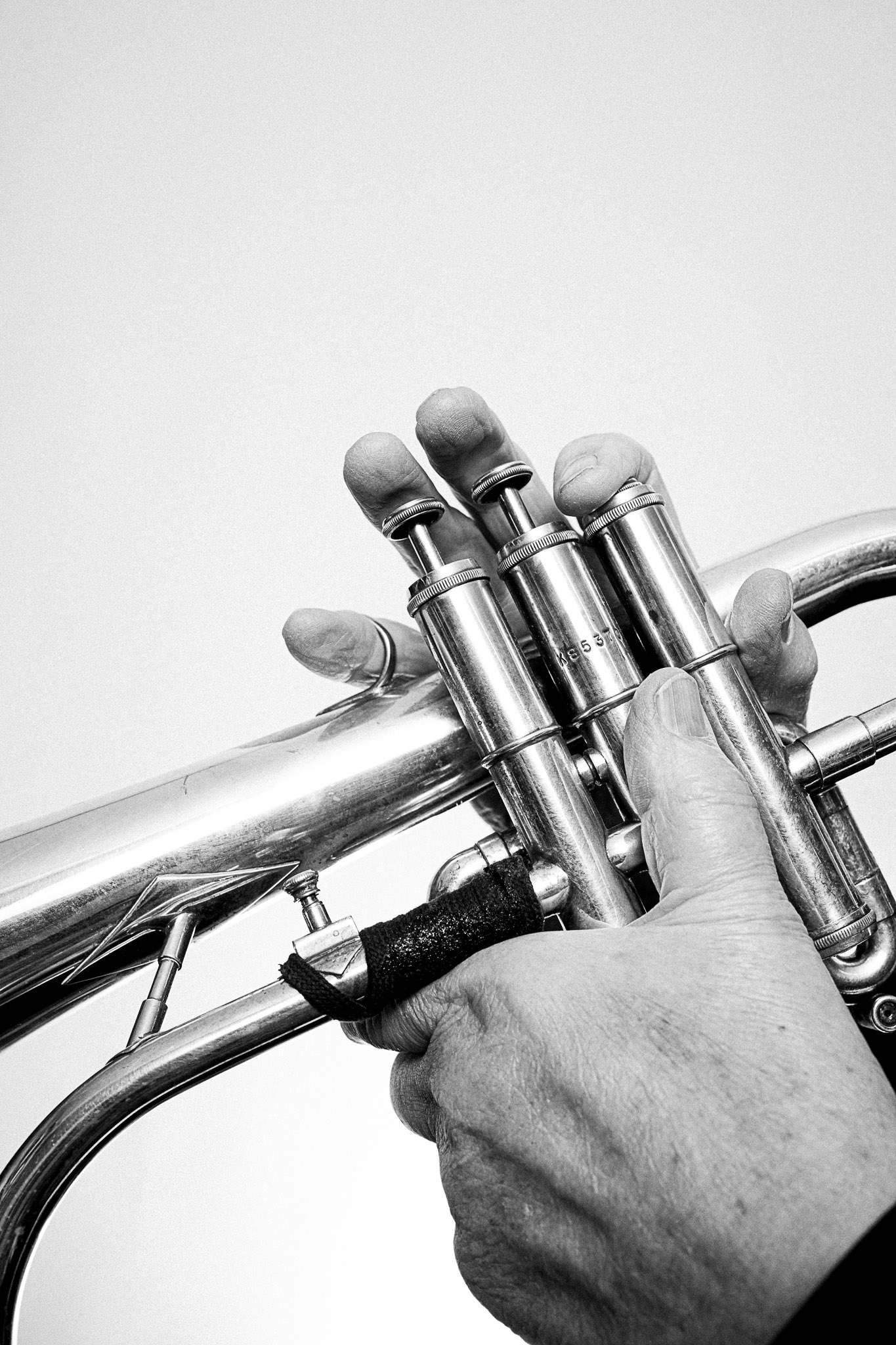 Close up black and white photograph of a musician playing a trumpet by Richard Mayle.