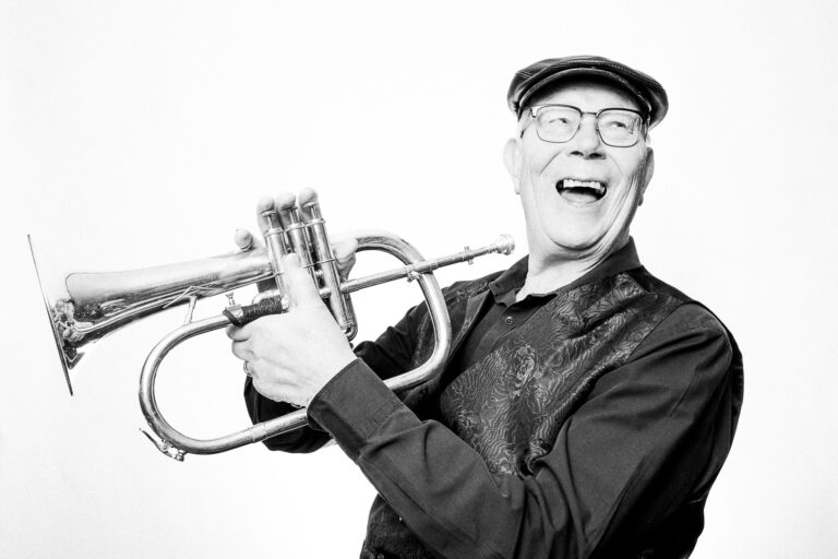 Black and white photograph of a musician laughing and holding a flugelhorn by Richard Mayle.