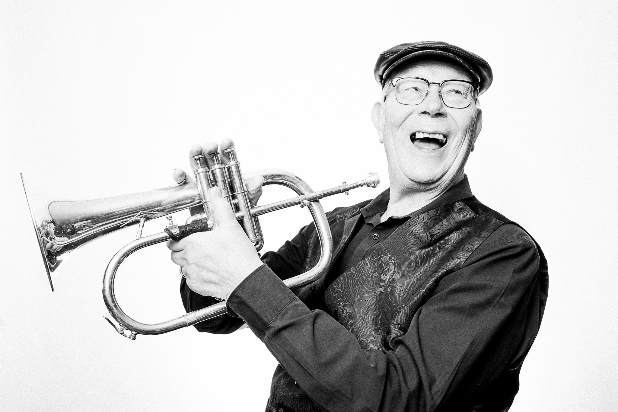Black and white photograph of a musician laughing and holding a flugelhorn by Richard Mayle.